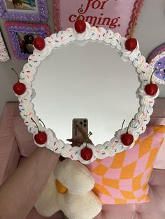 there is a mirror with cherries on it and a teddy bear in front of it