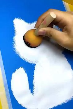 a person is painting an animal with white paint on blue and yellow paper that says happy easter