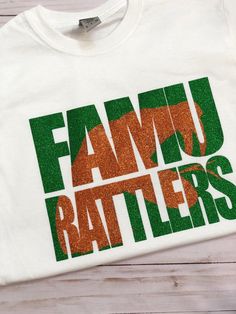 Custom shirt for a Proud FAMU Rattler made just for you!! It can be customized by request. Your choice of matte or glitter vinyl.   Listing is for a unisex short sleeve shirts. If you're interested in women sizes, racer backs, long sleeve, etc. (additional charge) please let me know in the comments.  Our current processing time is 5-7 business days plus shipping. Priority Mail can also be added to get faster delivery and add insurance on your order via the USPS.  Thanks for visiting!  If you hav Famu Rattlers, Get Faster, Short Sleeve Shirts, Glitter Vinyl, Custom Shirt, Unisex Shorts, Custom Clothes, Custom Shirts, Short Sleeve Shirt