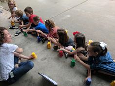 a group of children sitting on the ground playing with cups