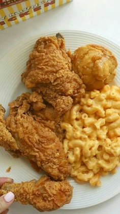 fried chicken, macaroni and cheese on a plate with a hand reaching for it