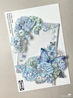 a card with blue flowers and a butterfly on the front, next to a photo frame