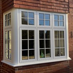 a brick building with two windows and a vase on the window sill next to it