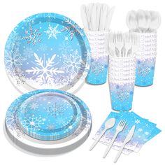 a table set with blue and white plates, silverware and napkins in the shape of snowflakes