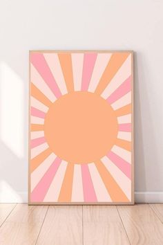 an orange and pink sunburst on a white wall in a room with hardwood floors