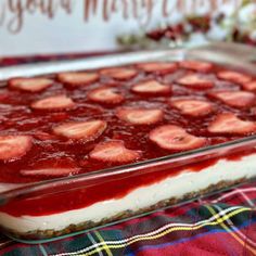 a strawberry cheesecake in a glass dish on a table