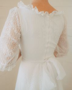 the back of a woman's white dress with ruffled sleeves