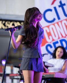 a woman standing in front of a microphone on stage