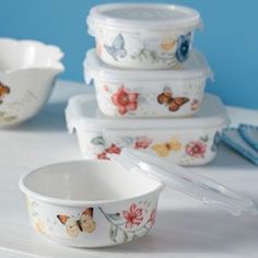 a stack of white bowls with butterfly designs on them and spoons next to each other