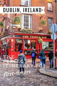 people walking in front of the temple bar on a cobblestone street with tall brick buildings