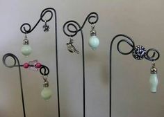 several earrings are displayed on black metal stands