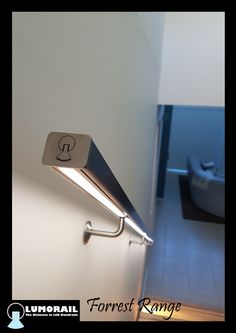 a wall mounted light on the side of a white wall next to a bed in a room