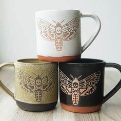 three coffee mugs with different designs on them