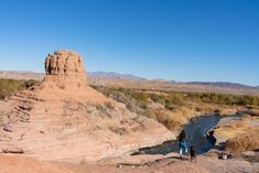 two people are standing on the edge of a river