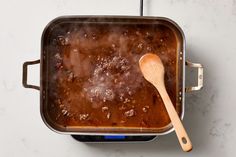 a wooden spoon sitting in a pan filled with food on top of a white counter