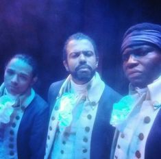 three men standing next to each other wearing turbans