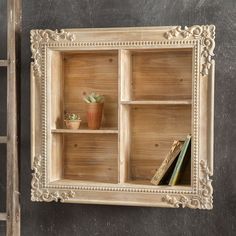 a wooden shelf with books and plants in it on the wall next to a ladder