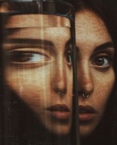 a woman's face is seen through a glass window with her nose piercings