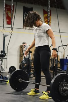 a woman with dreadlocks is lifting a barbell