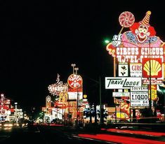 the neon signs are all lit up at night in front of an amusement park with clowns