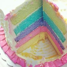 a multi - colored cake with one slice missing from it