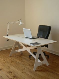 a laptop computer sitting on top of a white desk next to a black leather chair