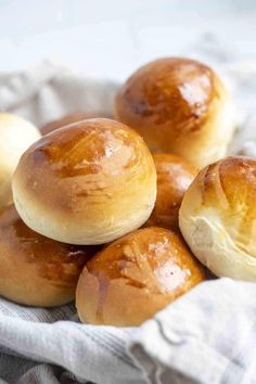 small rolls in a basket on top of a white cloth with some brown stuff around them