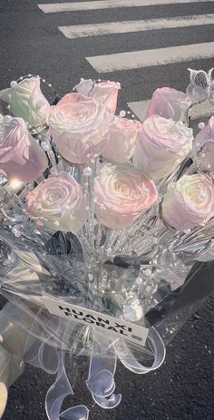 a clear vase filled with pink roses sitting on top of a table next to a cross walk