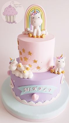 there is a pink and purple cake with unicorns on the top, and a rainbow in the middle