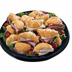 a platter filled with croissant sandwiches and ham