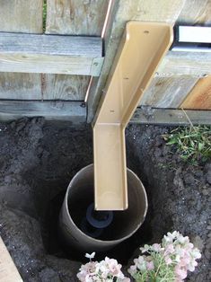 a potted plant in the ground next to a wooden bench with flowers growing out of it