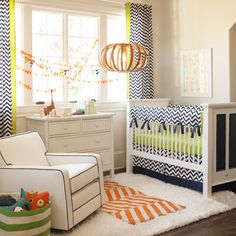 a baby's room is decorated in blue, orange and white