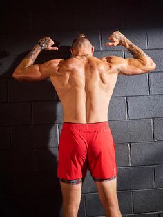 a man standing in front of a brick wall flexing his muscles