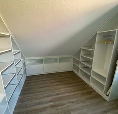 an attic bedroom with white shelving and wood flooring