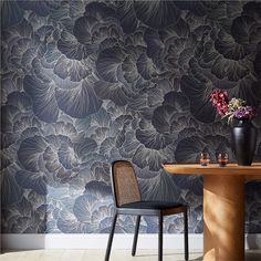 a table and chair in front of a wallpapered room with flowers on it