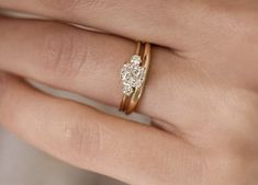 a woman's hand with a gold ring and two diamond engagement rings on it