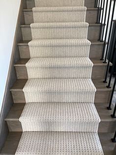 a white carpeted staircase with black handrails