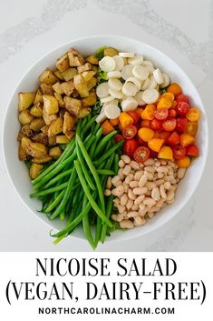 a white bowl filled with beans, green beans, tomatoes and other veggies