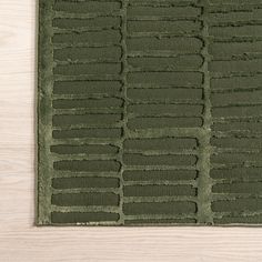 a green rug on top of a wooden floor