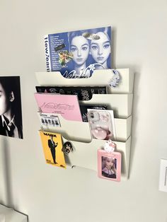 a white wall mounted shelf with pictures and magnets on it's sides, next to a toilet