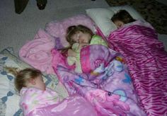 three children sleeping in blankets on the floor