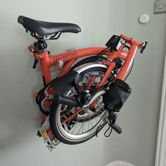 an orange bicycle is hanging on the wall