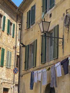 clothes hanging out to dry in front of an old building with green shutters and windows