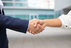 two people shaking hands in front of a building