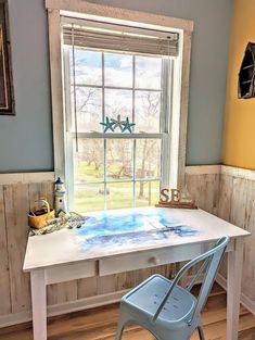 a white table and chair in front of a window with blue paint painted on it