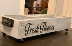 a wooden box with the words fresh flowers on it sitting on top of a table