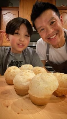 a man and boy posing for a picture with some breads on the table in front of them