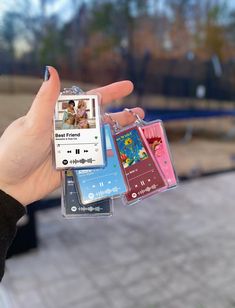 a person holding three different colored cell phones in their hand, one with an mp3 player attached to it