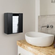 a bathroom sink sitting under a mirror next to a wall mounted paper dispenser