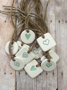 white ceramic hearts with green heart on them are tied up against a wooden background and string